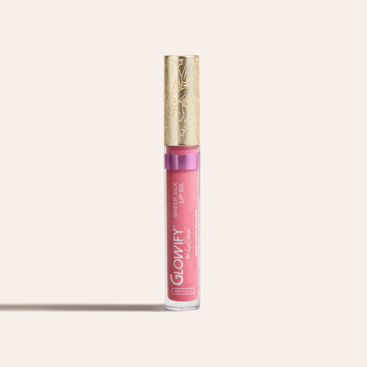 Pink sheer silk lip oil in a clear tube with a gold decorative cap standing upright
