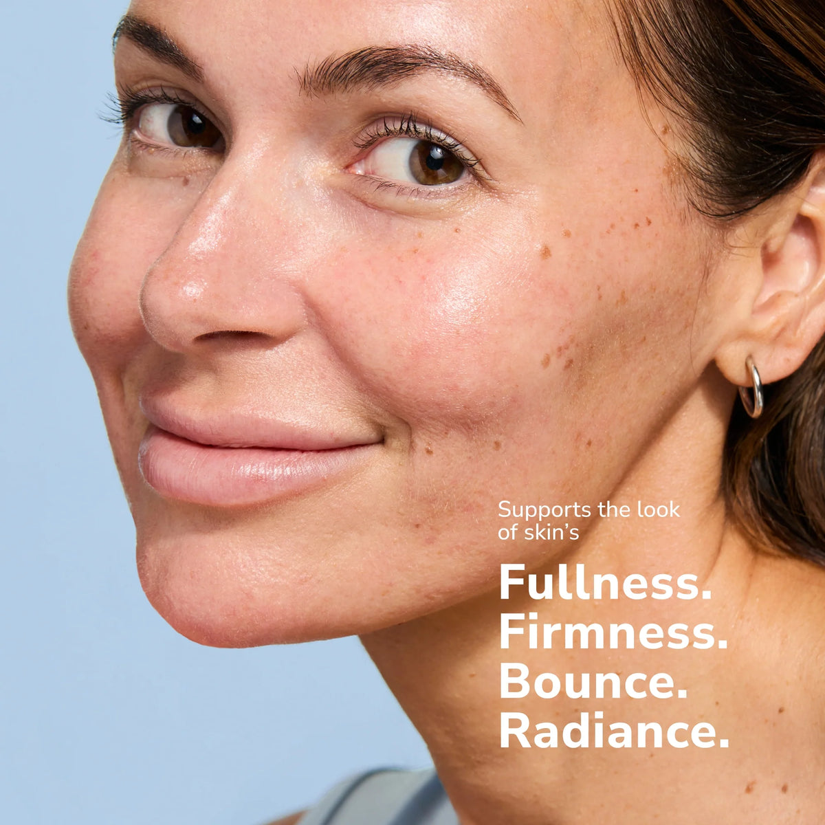 Close-up of a smiling woman with clear skin and freckles showing skincare results